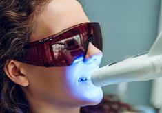 Zahnbleaching mit Blaulicht bei einer Patientin mit Schutzbrille