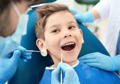 Junge auf Zahnarztstuhl lacht während der Untersuchung